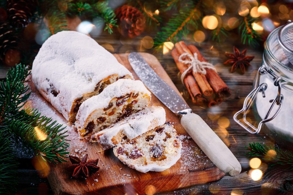 stollen on a cutting board with knife and cinnamon sticks